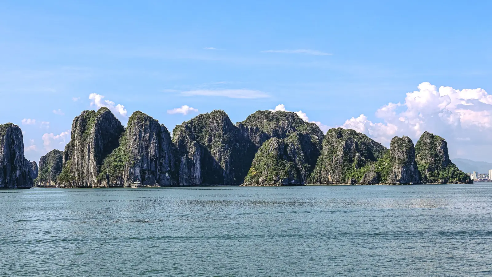 Limestone karst islands rising from the emerald water of Ha Long Bay under a clear sky